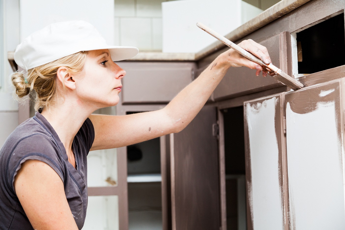 Closeup of Woman Holding Paint Brush and Painting Kitchen Cabinets for Home Painting in Portage.