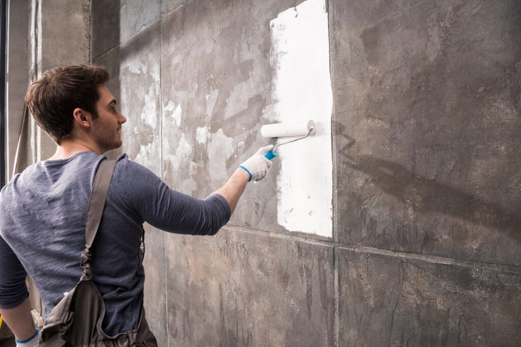 A young man provides basement painting services in Kalamazoo for a home.