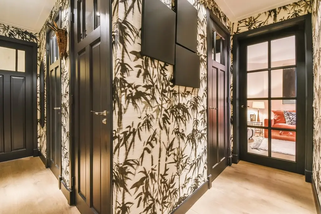 A corridor entrance to a house with palm tree wallpaper covering the walls.