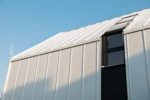 A metal hangar with a metal roof against the blue ski.