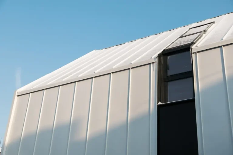A metal hangar with a metal roof against the blue ski.