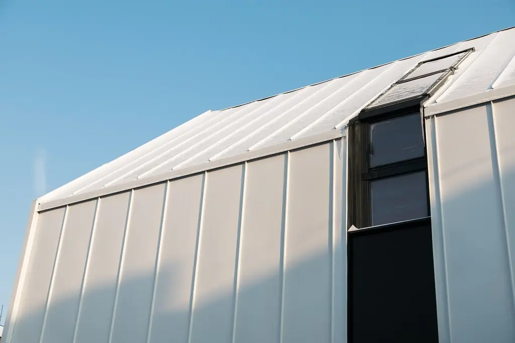 A metal hangar with a metal roof against the blue ski.