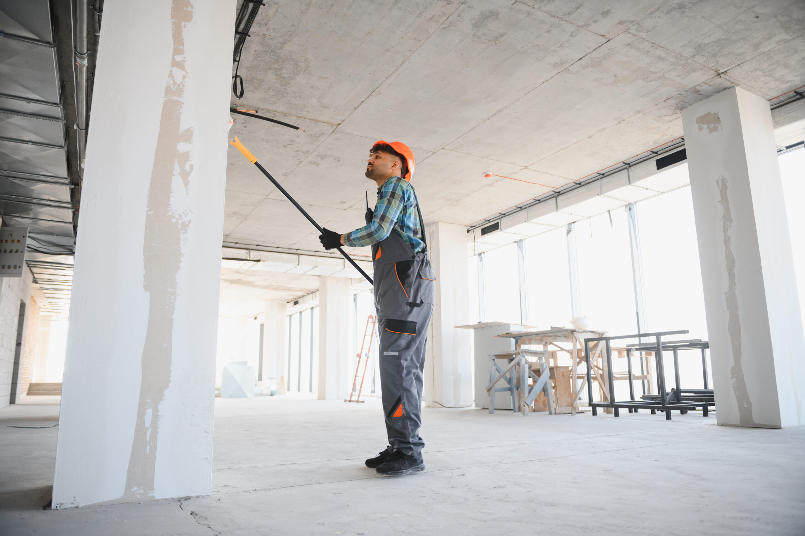 Construction worker applying a coat of paint on a wall using a roller, working diligently on a building site