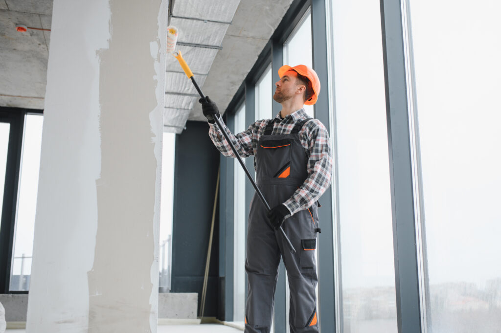 Professional builder applying a paint roller while decorating the interior of a newly constructed apartment, showcasing skill and precision
